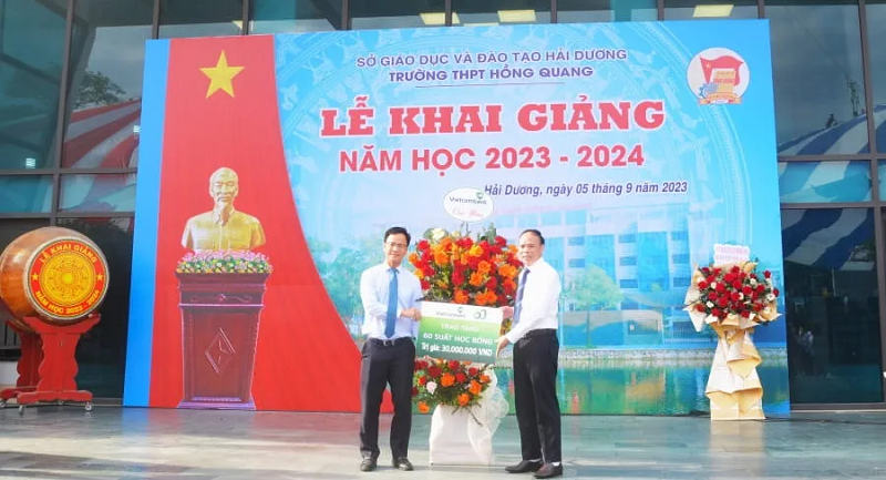 Đại diện Vietcombank Hải Dương, ông Vũ Tiến Dũng - Phó Giám đốc tặng hoa và trao biển tài trợ tượng trưng cho đại diện Ban Giám hiệu trường THPT Hồng Quang