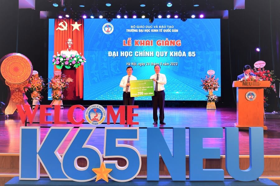 Ông Lê Quang Vinh - Phó Tổng Giám đốc Vietcombank (bên phải) trao biển tượng trưng số tiền 200 triệu tặng sinh viên Đại học Kinh tế quốc dân cho PGS., TS, Bùi Huy Nhượng - Phó Hiệu trưởng  Nhà trường