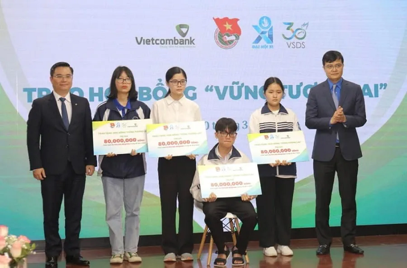 Ông Bùi Quang Huy - Bí thư thứ nhất Trung ương Đoàn (ngoài cùng bên phải) và ông Nguyễn Thanh Tùng - Tổng Giám đốc Vietcombank (ngoài cùng bên trái) trao học bổng "Vững bước tương lai" loại A tặng học sinh, sinh viên xuất sắc