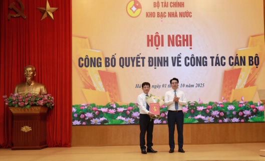 Giám đốc KBNN Trần Quân trao quyết định và tặng hoa chúc mừng tân Trưởng Ban Nguyễn Chí Vương.