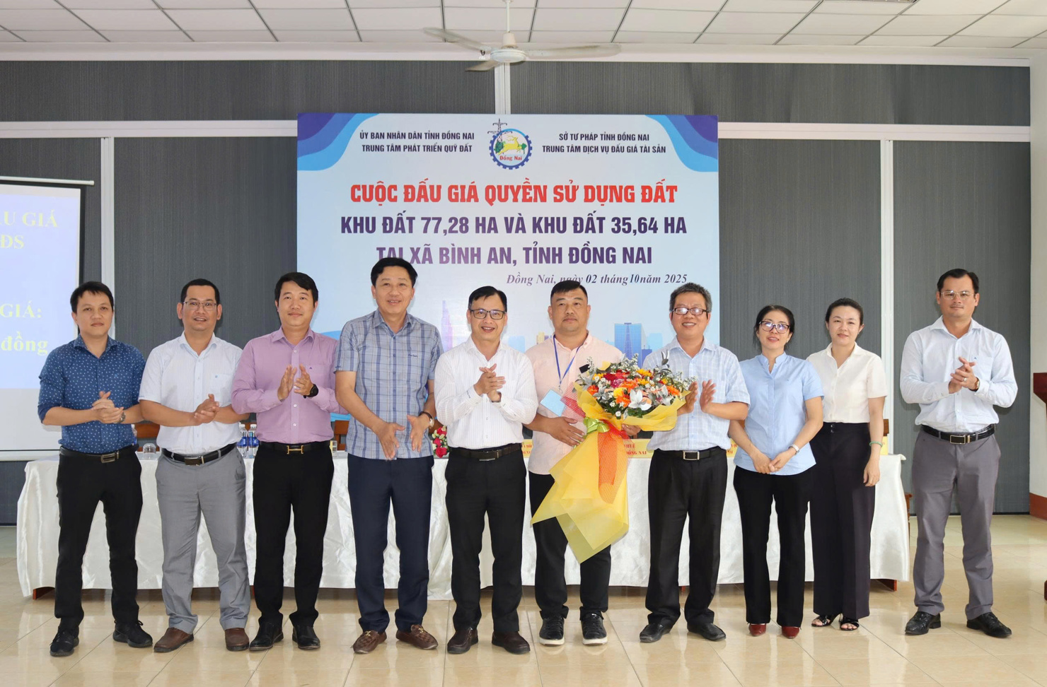 Đại diện Trung tâm Phát triển quỹ đất tỉnh và các sở, ngành tặng hoa chúc mừng khách hàng trúng đấu giá quyền sử dụng đất. Ảnh: HL