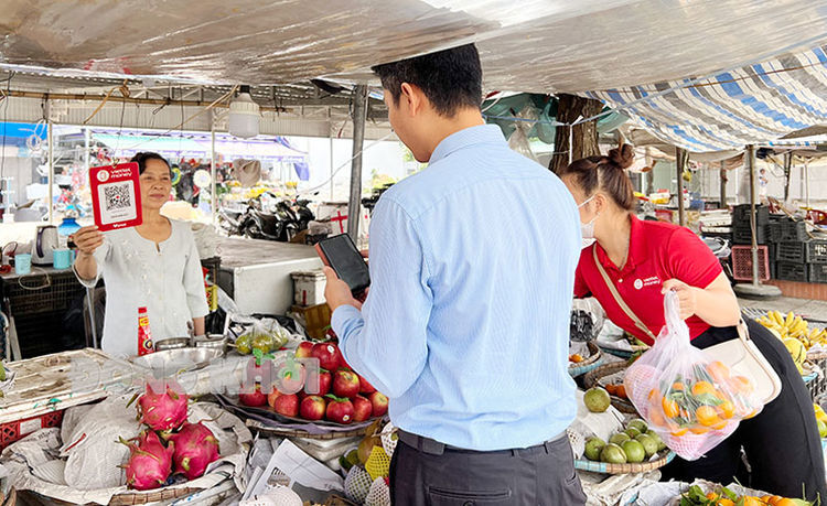 Tiểu thương chợ Ba Tri thực hiện ứng dụng mã QR Code để người dân thanh toán không dùng tiền mặt. Ảnh: Trung Trí
