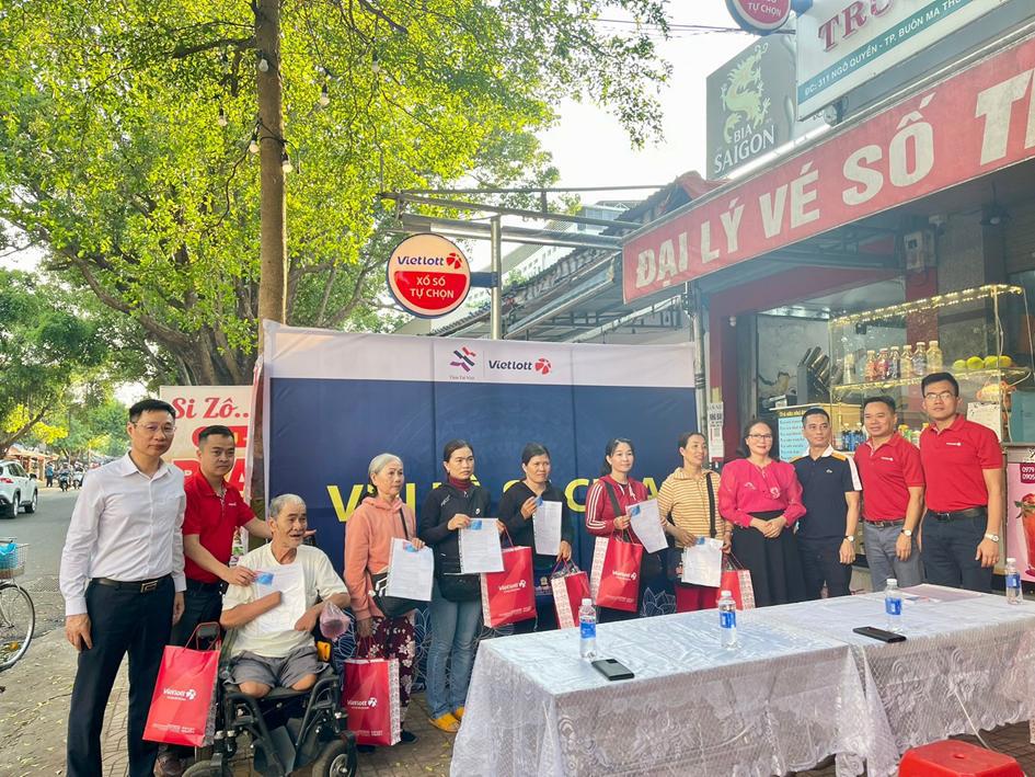 Đại diện Vietlott và đại diện Quỹ Tâm Tài Việt trao thẻ bảo hiểm cho điểm bán hàng xổ số tự chọn và người phân phối vé số.