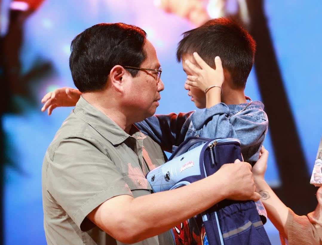 Thủ tướng lên sân khấu động viên, tặng quà cháu Nguyễn Quốc Bảo mồ côi do mưa lũ. Ảnh: VGP/Nhật Bắc 