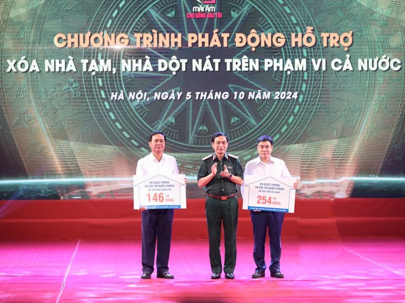 Bộ trưởng Bộ Quốc phòng Phan Văn Giang trao kinh phí của Bộ Quốc phòng và các doanh nghiệp quốc phòng ủng hộ các địa phương xoá nhà tạm, nhà dột nát. Ảnh VGP/Nhật Bắc