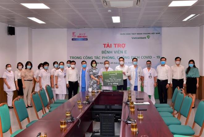 Tổng Giám đốc Vietcombank Phạm Quang Dũng (thứ 6 từ phải sang) cùng Đoàn công tác trao biển tượng trưng số tiền 2 tỷ đồng cho bác sỹ Lê Ngọc Thành - Giám đốc cùng các y bác sỹ Bệnh viện E