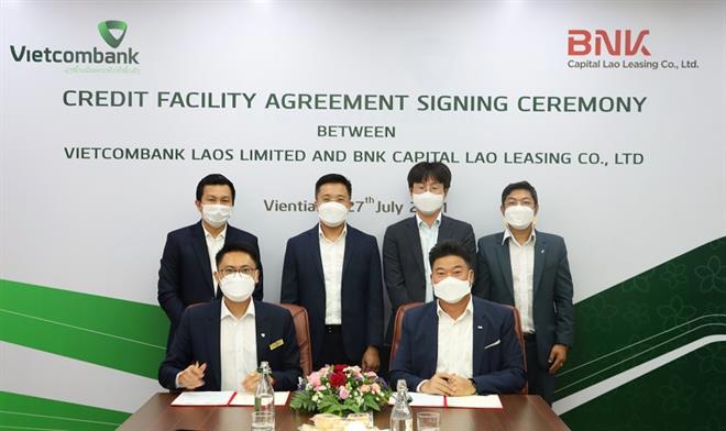 Ông Wiley KHOTNHOTHA - Phó Tổng Giám đốc Vietcombank Lào (bên trái) và ông Jeongsoo Ha - Tổng Giám đốc BNK Lào (bên phải) thực hiện ký kết hợp đồng tín dụng
