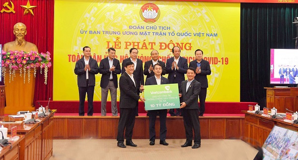 Ông Nghiêm Xuân Thành – Chủ tịch HĐQT Vietcombank (đứng giữa) trao biển tượng trưng số tiền ủng hộ công tác phòng, chống dịch COVId-19 của Vietcombank
