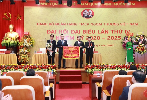 Đ/c Y Thanh Hà Niê Kđăm - Ủy viên dự khuyết Ban Chấp hành Trung ương Đảng, Bí thư Đảng ủy Khối DNTW (bên phải) trao Cờ thi đua của Đảng ủy Khối tặng Đảng bộ Vietcombank đạt thành tích xuất sắc nhiệm kỳ 2015-2020