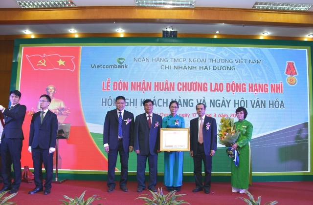 Ông Bùi Thanh Quyến, UV BCHTW Đảng, Bí thư Tỉnh ủy, Chủ tịch HĐND tỉnh Hải Dương (thứ 2 từ trái sang) và Phó Thống đốc thường trực Nguyễn Đồng Tiến (thứ 2 từ phải sang) trao Huân Chương Lao động hạng Nhì và tặng hoa cho Ban Giám đốc Vietcombank Hải Dương