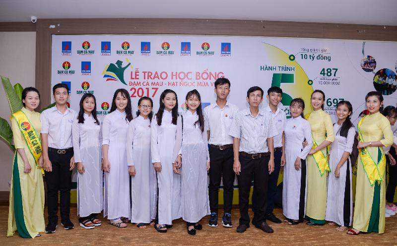 Các em học sinh chụp hình lưu niệm trên bức tường hành trình 5 năm của quỹ học bổng Đạm Cà Mau – Hạt Ngọc Mùa Vàng