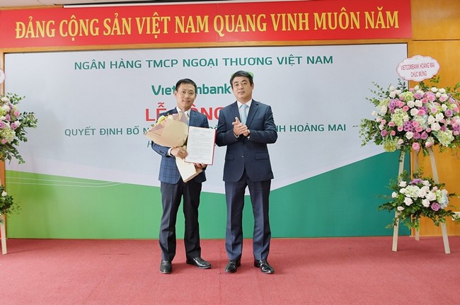 Ông Nghiêm Xuân Thành - Bí thư Đảng ủy, Chủ tịch HĐQT Vietcombank (bên phải) trao quyết định và tặng hoa chúc mừng ông Đặng Kiên Định – tân Giám đốc Vietcombank Hoàng Mai
