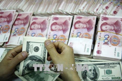 Đồng tiền giấy 100 Nhân dân tệ (trái) và đồng USD. Ảnh: Reuters