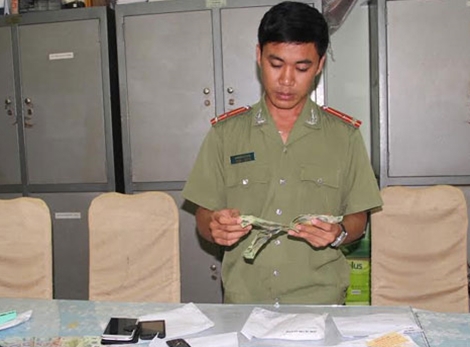 Điều tra viên kiểm tra tang vật tiền giả thu giữ trong vụ án. Nguồn: cand.com.vn