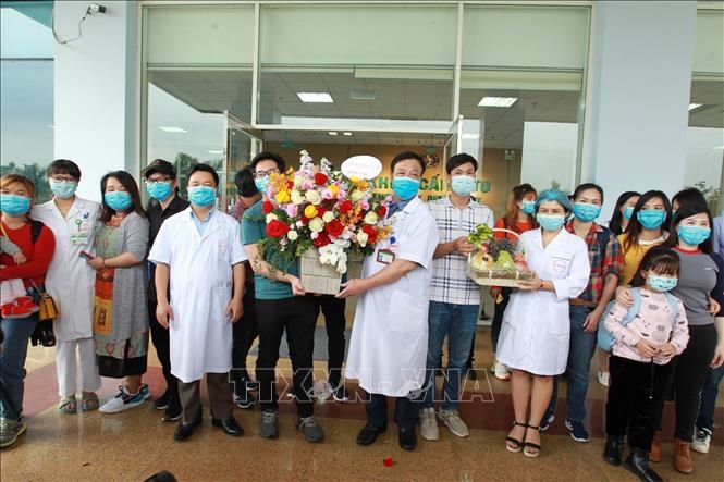 Cán bộ, bác sỹ Bệnh viện Nhiệt đới Trung ương tặng hoa chúc mừng 30 người trở về từ Vũ Hán (Trung Quốc) hoàn thành thời gian cách ly, ngày 2/3/2020. (Ảnh: Minh Quyết/TTXVN)