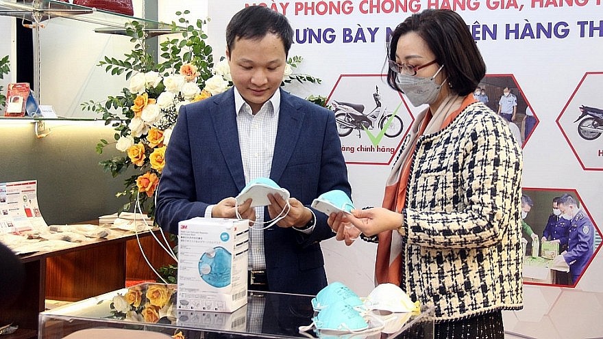 Người dân tìm hiểu cách phân biệt hàng thật- hàng giả tại phòng trưng bày của Cục Quản lý thị trường Hà Nội tổ chức vào cuối tháng 11/2021 tại Hà Nội. Ảnh: CTV QLTT