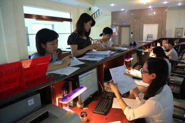 Cán bộ KBNN đang giải đáp các thắc mắc của khách hàng đến giao dịch với kho bạc.
