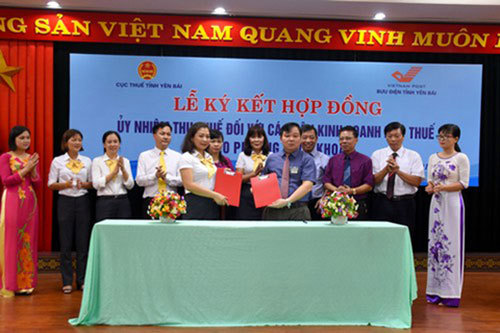 Ông Nông Xuân Hùng, Cục trưởng Cục Thuế và bà Nguyễn Thị Thanh Hương, Giám đốc Bưu điện tỉnh Yên Bái trao hợp đồng đã được ký kết giữa hai bên. Ảnh: Dũng Hà