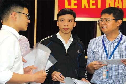 Cán bộ Cục Thuế Hà Nội (phải) hỗ trợ người nộp thuế làm thủ tục quyết toán thuế TNCN tại trụ sở chính Vietcombank.